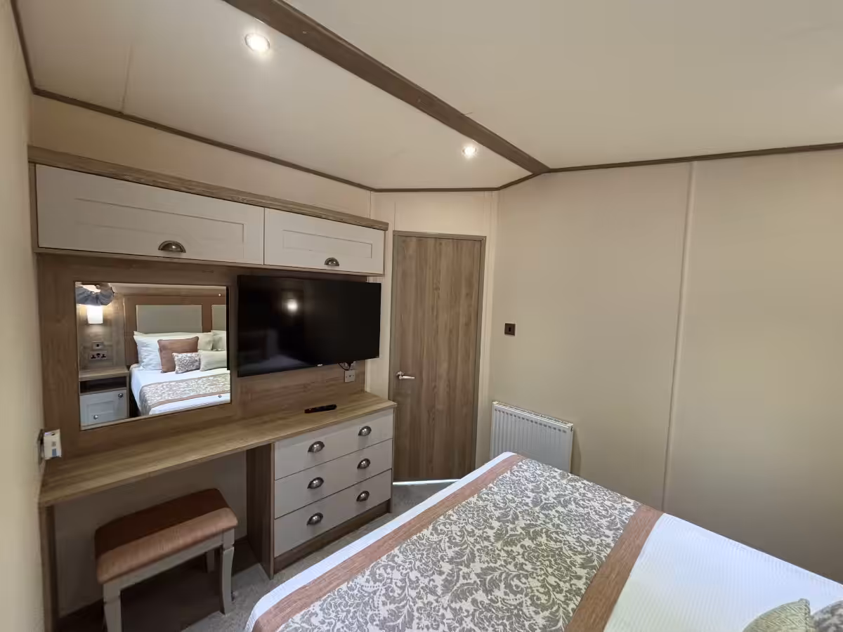 Master bedroom view on TV and storage in the 2021 ABI Adderstone Elite for sale at Elm Bank Coastal Park in Berwick, Northumberland.